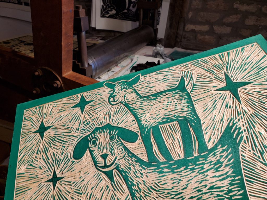 close up of finished carved woodcut of baby goat standing on mama goat's back