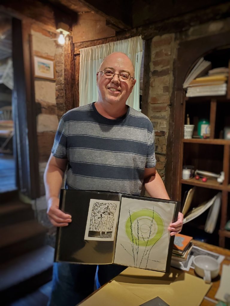 printmaker Arnold Pennington holding his portfolio