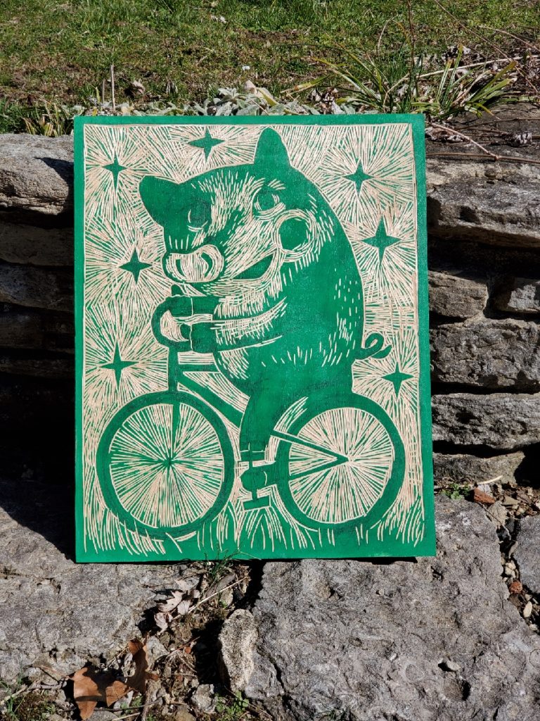 partially carved woodcut of pig on bicycle