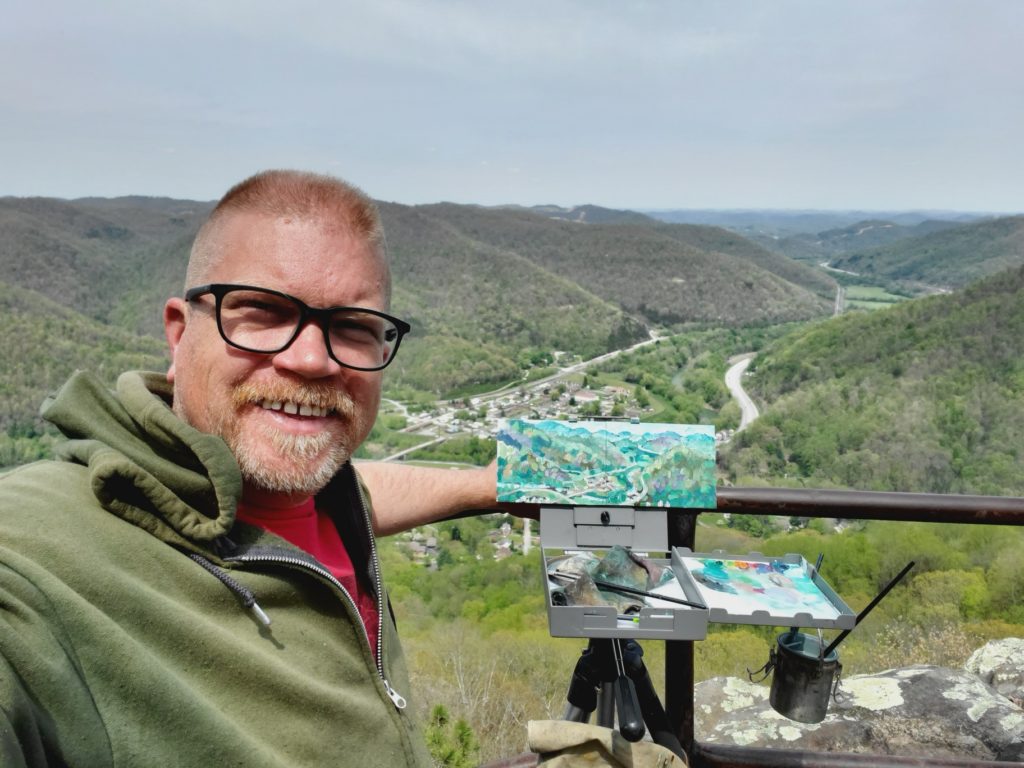 artist standing with plein air painting from view on top of pine mountain