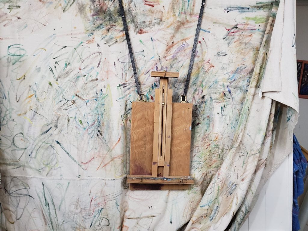 french easel modified to hang on a wall with canvas backdrop