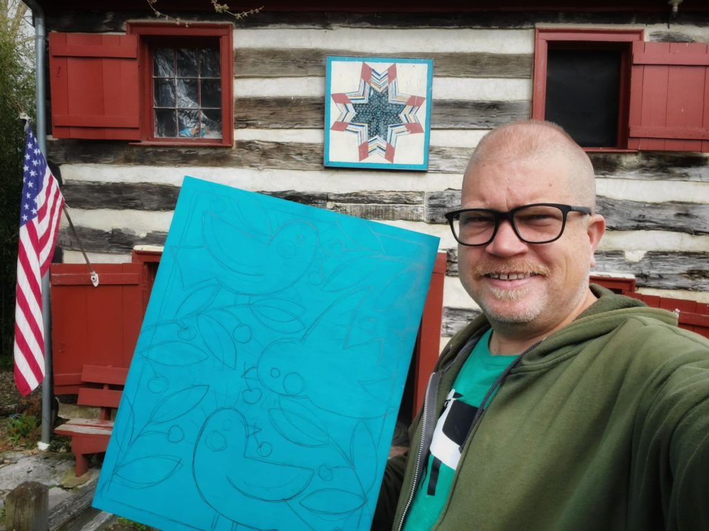 ken swinsos holding woodcut work in progress of birds eating cherries