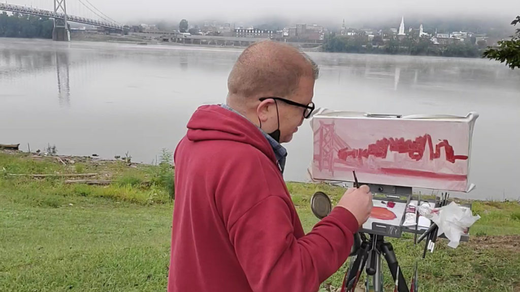 photo of artist painting landscape from the ohio river