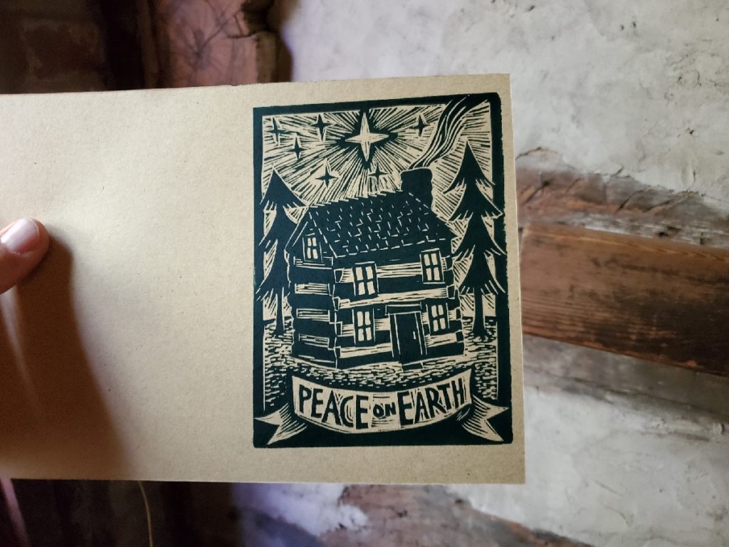 notecard of log cabin with star shining over it includes text: peace on earth