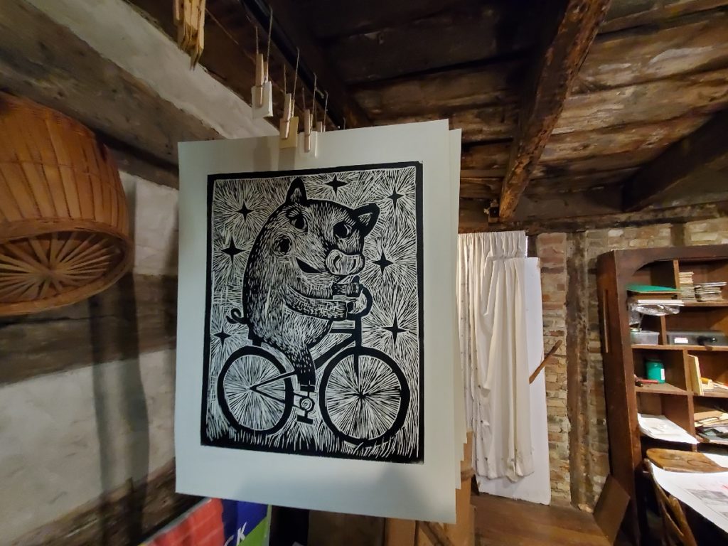 woodcut of pig on bicycle hanging to dry