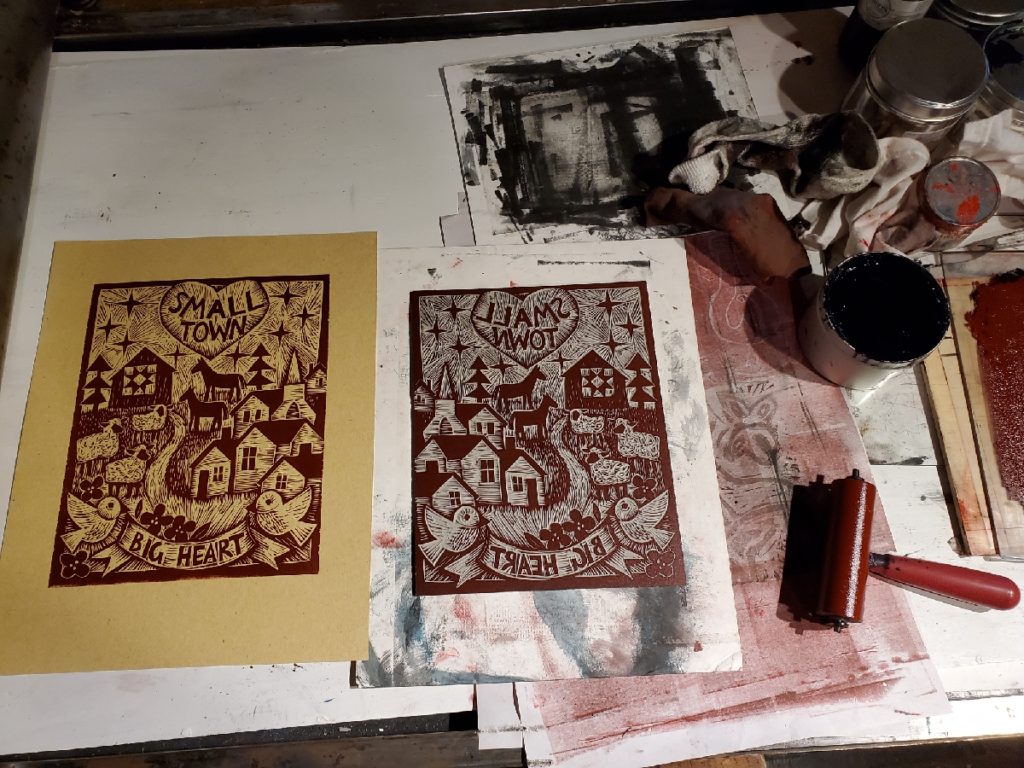 first proof of linocut with a village, sheep, horses and birds