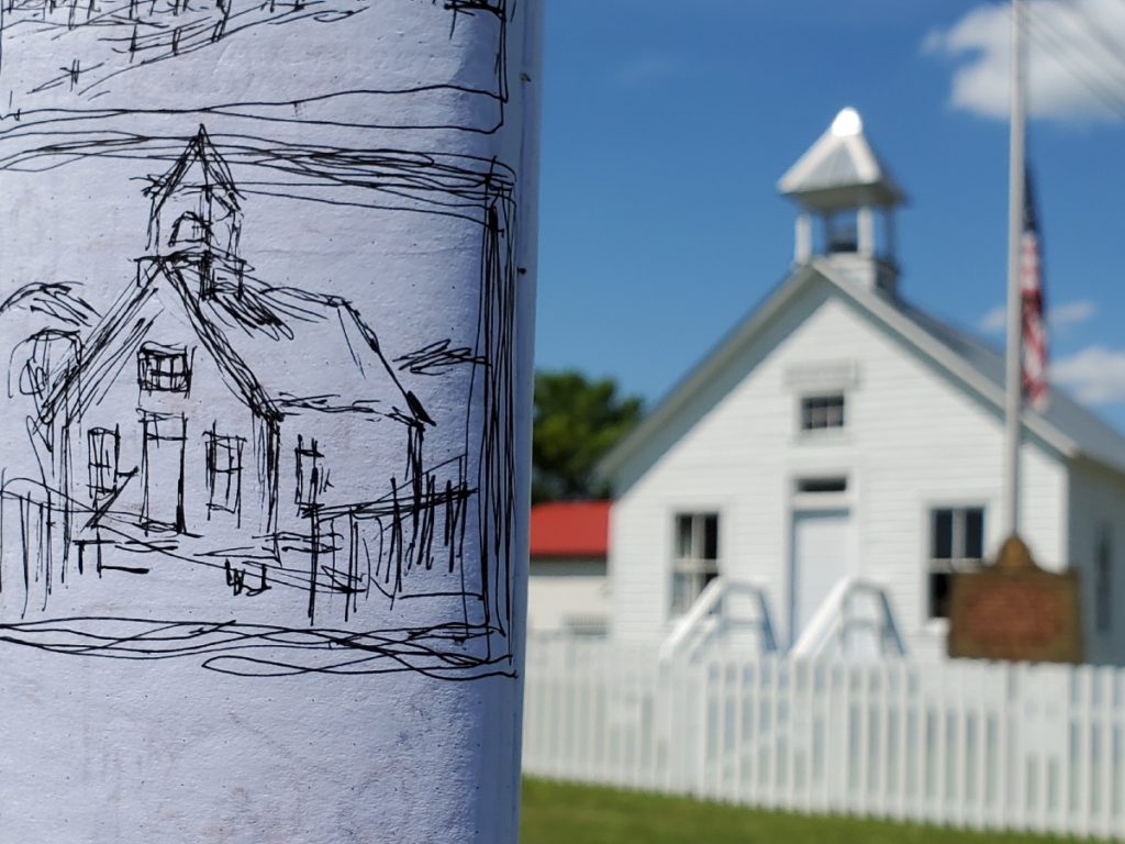 a sketch held beside photo of the moonlight school in morehead kentucky