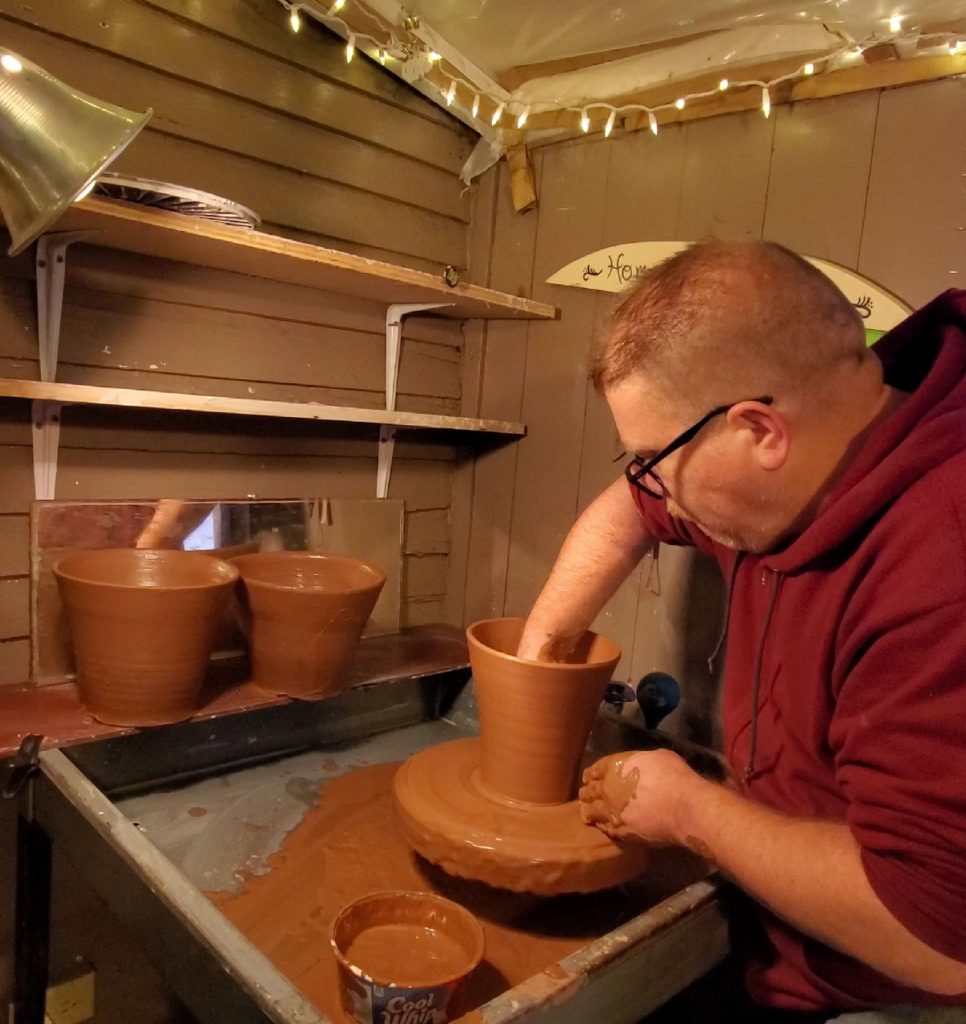 potter throwing clay flowerpots on wheel