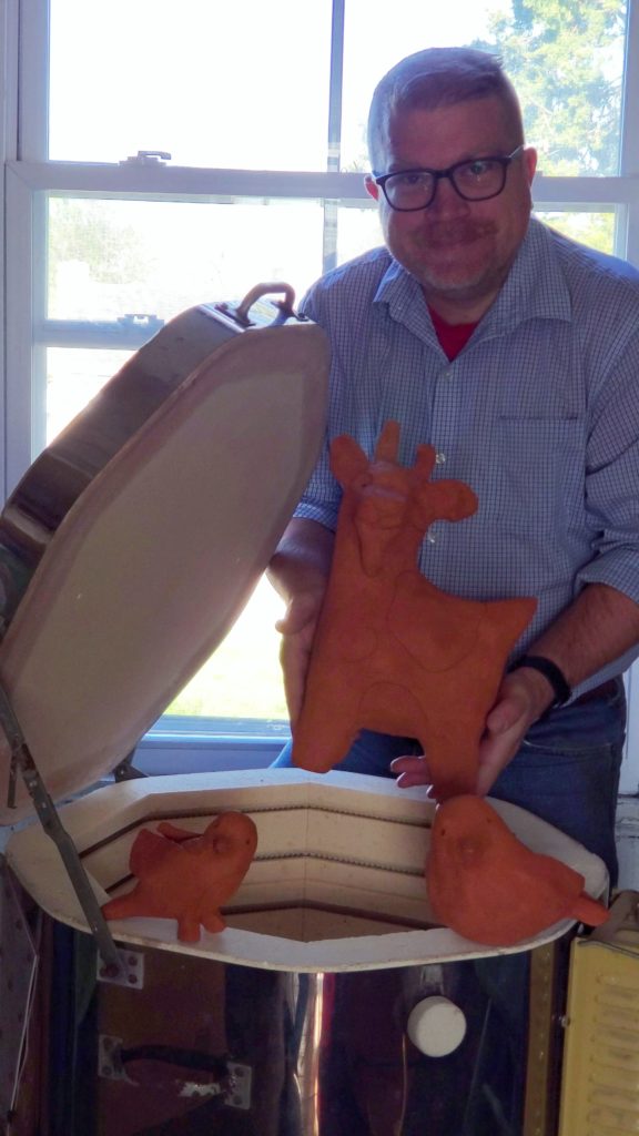 artist holding goat shaped sculpture from kiln