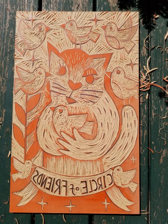 work in progress woodcut of a cat holding a bird ready to print