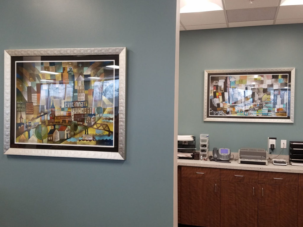 ken swinson cincinnati paintings framed an on display over a desk