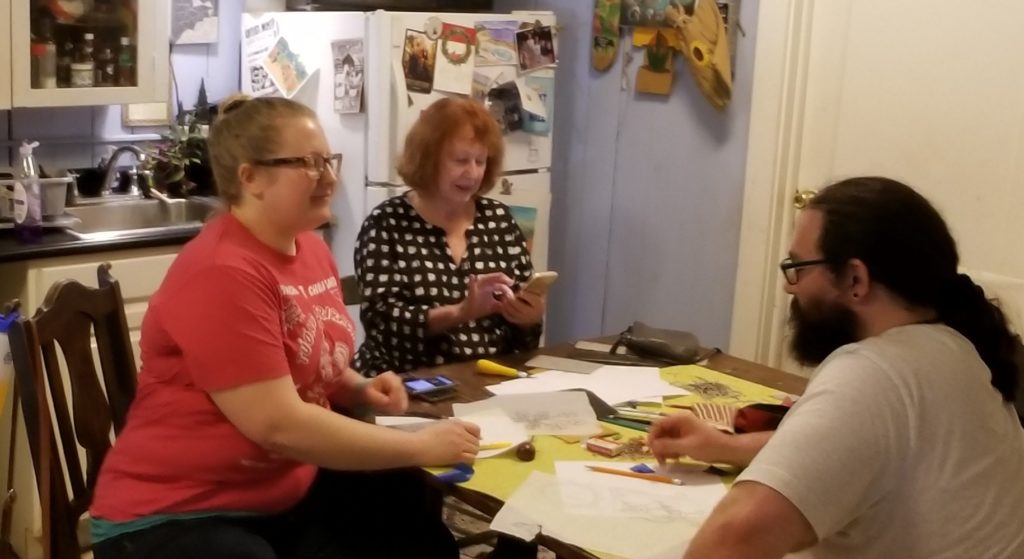 friends sitting together making linocut prints