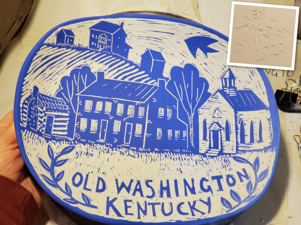 porcelain plate with sgraffito design of Old Washington, Kentucky. Log Cabin, Federal Brick buildind and white church house.