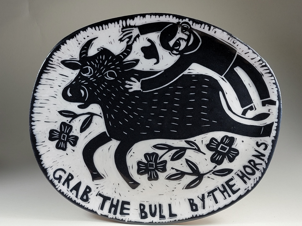 porcelain plate of man holding on to a bull's horn black sgraffito design