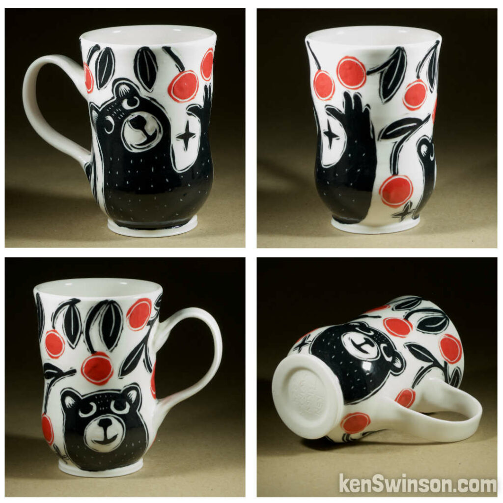 A wheel thrown porcelain cappuccino cup made by Kentucky artist, ken swinson-the bowl is decorated with black, white and red sgraffito design of a bear picking cherries.