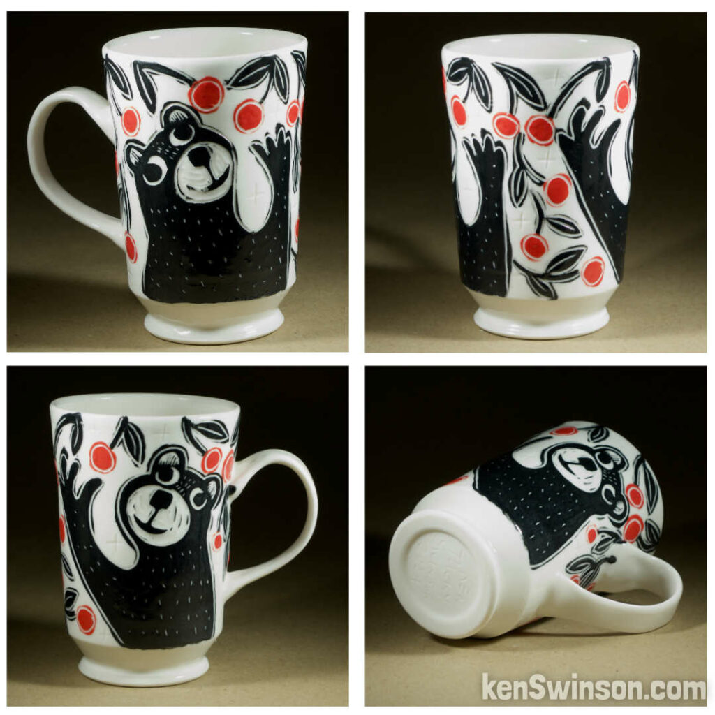 A wheel thrown porcelain cappuccino cup made by Kentucky artist, ken swinson-the bowl is decorated with black, white and red sgraffito design of a bear picking cherries.