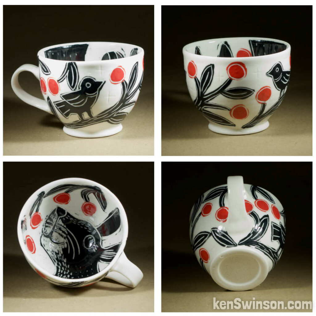 A wheel thrown porcelain cappuccino cup made by Kentucky artist, ken swinson-the bowl is decorated with black, white and red sgraffito design of birds eating cherries on the exterior. the interior has a bunny eating red cherries