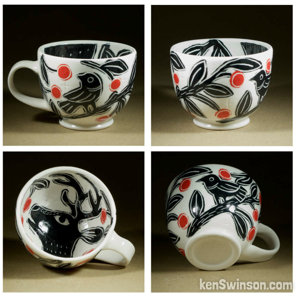 A wheel thrown porcelain cappuccino cup made by Kentucky artist, ken swinson-the bowl is decorated with black, white and red sgraffito design of birds eating cherrieson the exterior. the interior has a deer eating red cherries