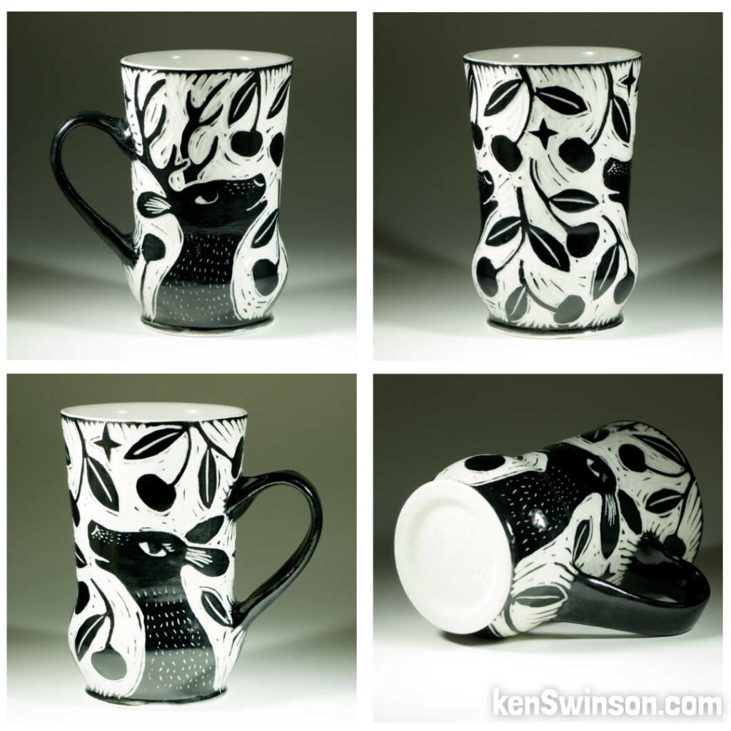 A wheel thrown porcelain cup with black and white sgraffito design of two deer eating cherries from a tree