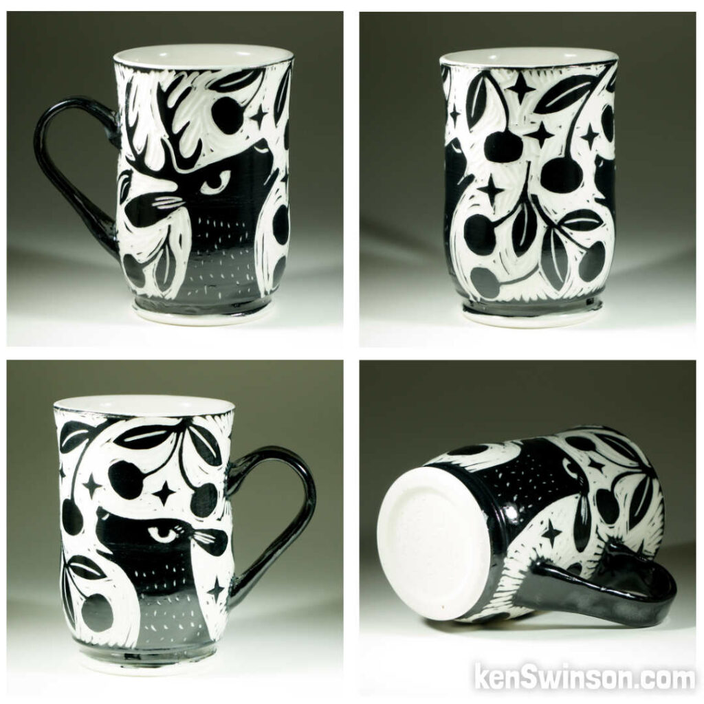 A wheel thrown porcelain cup with black and white sgraffito design of two deer eating cherries from a tree