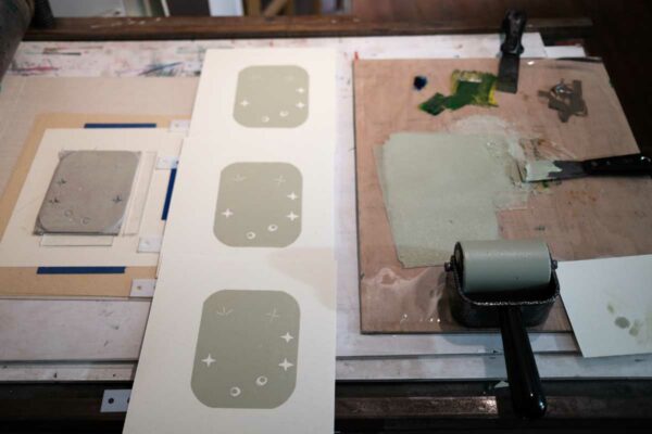 a block, 3 prints and a slab of light green ink. The first layer of a 3 layer reduction linocut